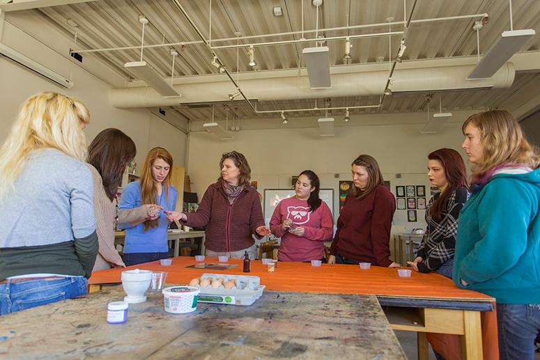 A professor works with students in the art education studio