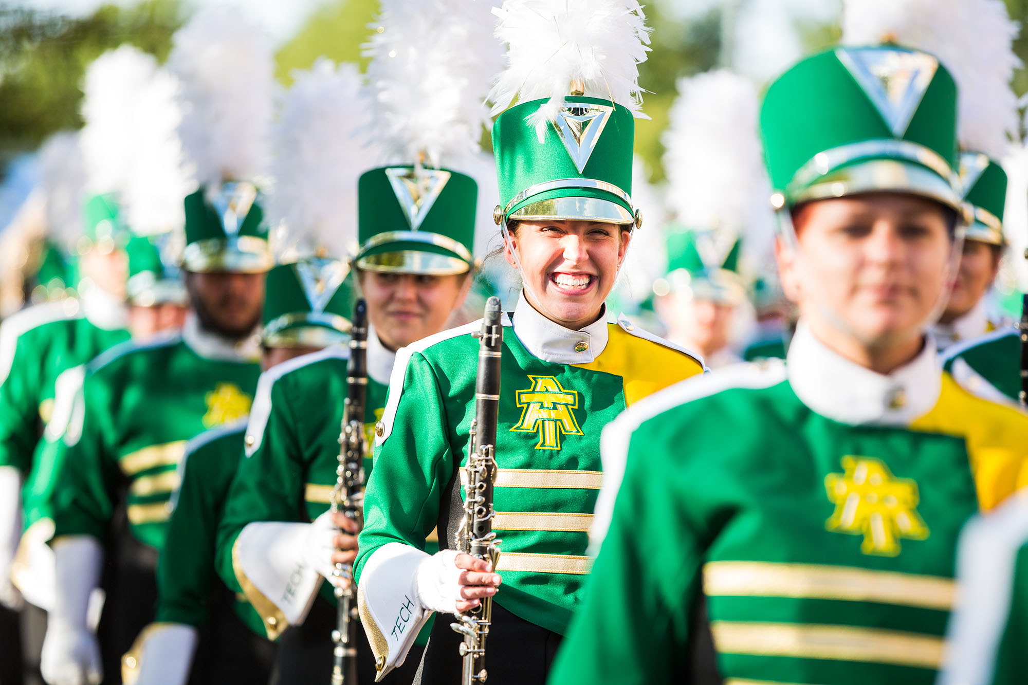 a female musician smiles for the camera as the marching band walks by on their way to the football field