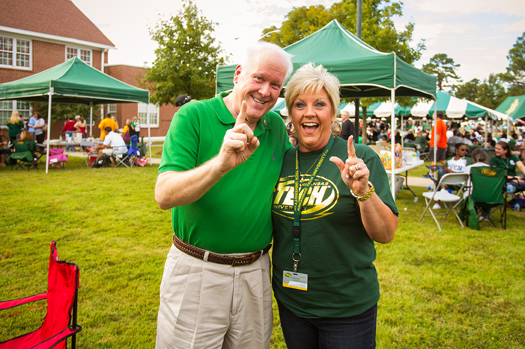 Two people dressed in Arkansas Tech garb pose at an outdoor event