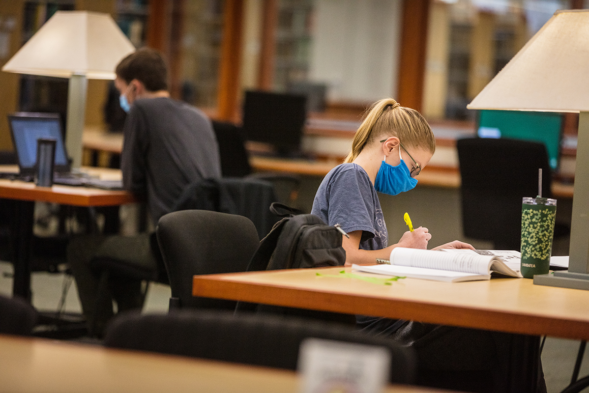 A student studying some papers in front of a computer