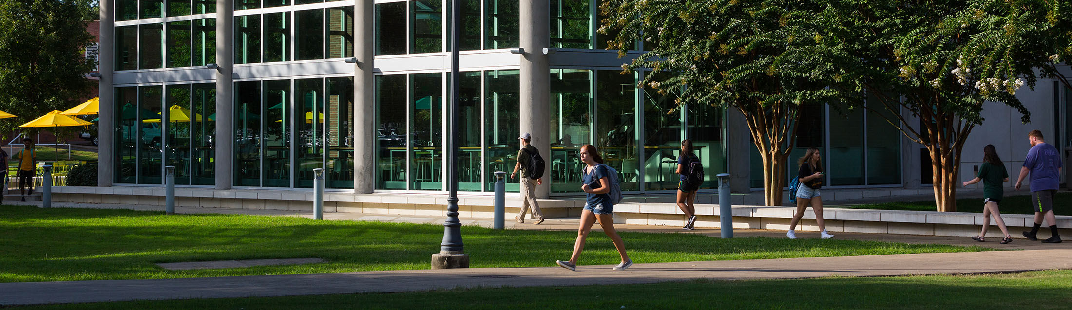 a student walking on campus in front of baswell techionery