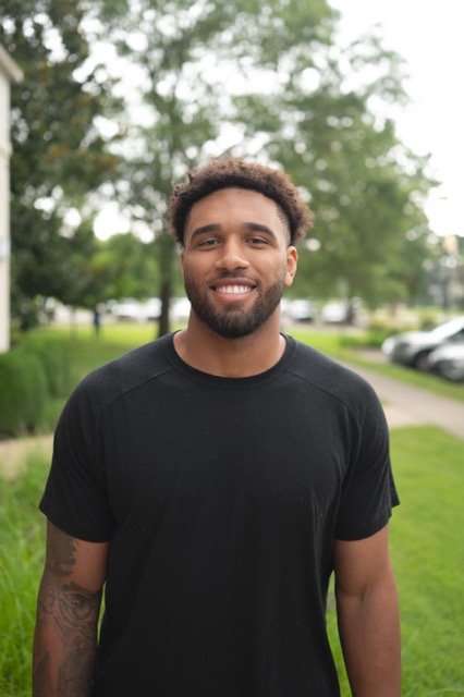 The head and torso of a smiling black man. 